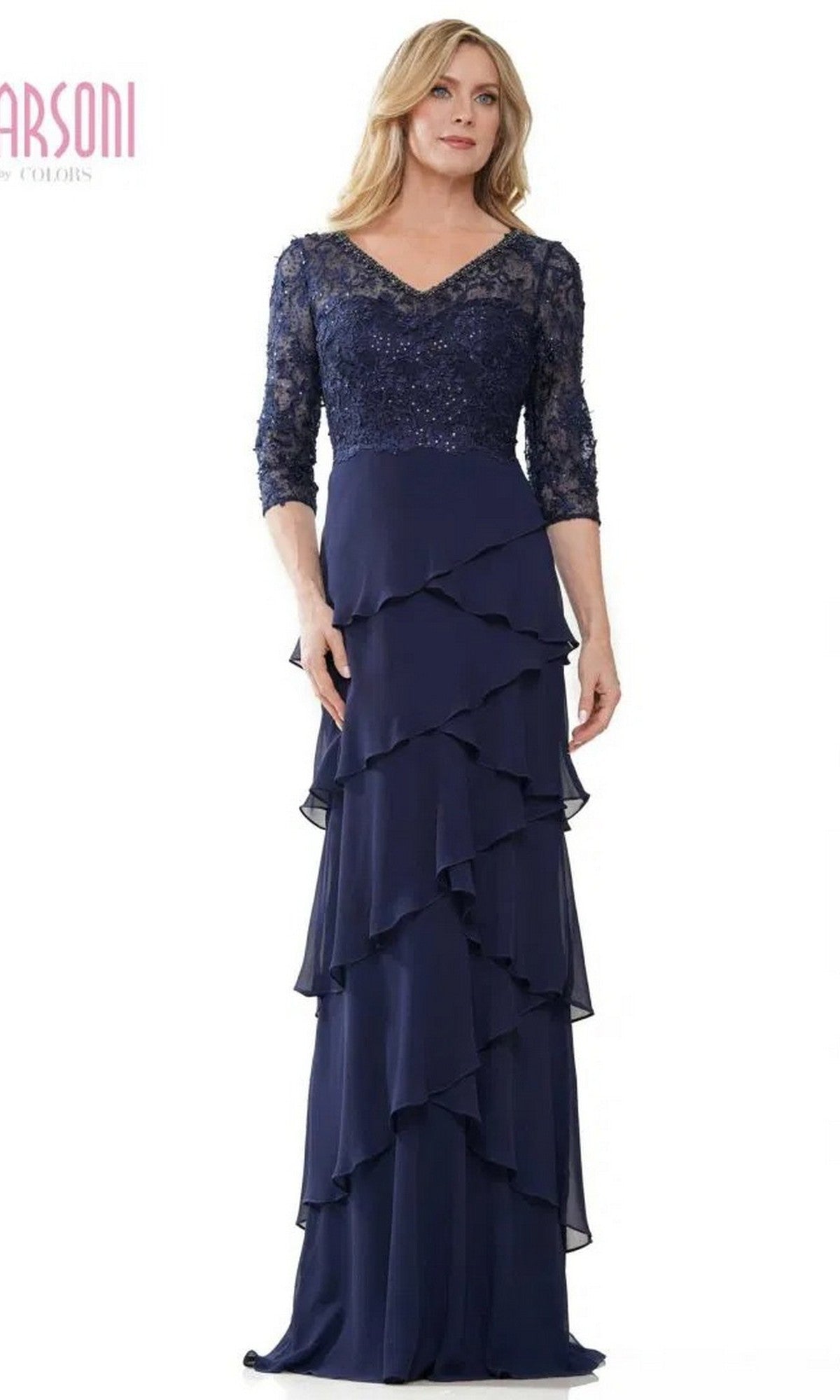 A woman stands against a white background wearing the Marsoni MV1244 long formal dress in navy, featuring a lace embroidered bodice, three-quarter sleeves, and a layered ruffle skirt.
